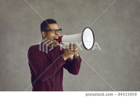 Excited agitated crazy young black man yelling in marketing megaphone informing about big sale at shopping center. Angry Afro American guy with sound amplifier shouting announcing BLM strike action 84315959