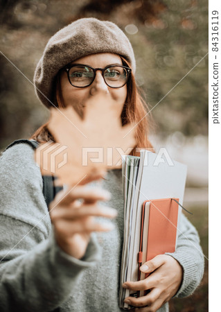Beautiful female college student with books walking in a park Beautiful female college student with books walking in a park 84316119