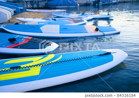 Stand up SUP paddle board on lake or sea with blue water lilies, paddling in summer time at sunset. Summer family vacation 84316184