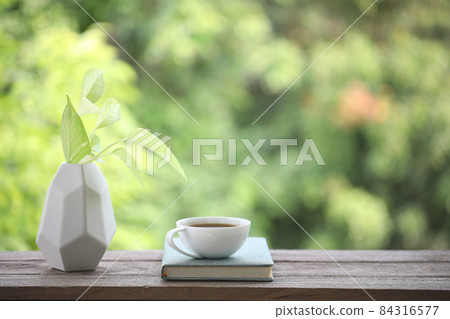 White coffee cup and notebook with devil ivy plant on wooden table White coffee cup and notebook with devil ivy plant on wooden table 84316577