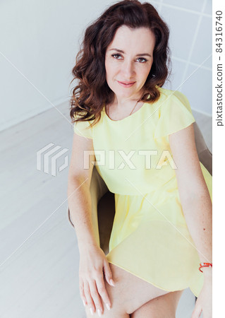 portrait of a beautiful brunette woman in a yellow dress at home 84316740