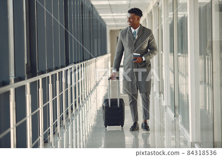 Elegant black man at the airport with a suitcase 84318536