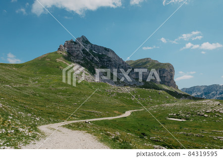 Amaizing view on Durmitor mountains, National Park, Mediterranean, Montenegro, Balkans, Europe. Bright summer view from Sedlo pass. The road near the house in the mountains. Amaizing view on Durmitor mountains, National Park, Mediterranean, Montenegro, Balkans, Europe. Bright summer view from Sedlo pass. The road near the house in the mountains. 84319595