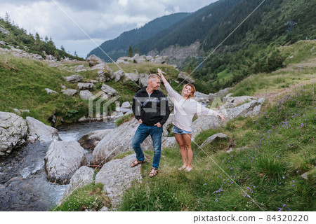 Romantic summer love story on a sunset in mountains. Young girl and boy in love. 84320220