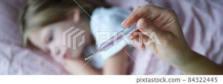 Woman hand holding mercury thermometer with high temperature on background of child sick with flu closeup Woman hand holding mercury thermometer with high temperature on background of child sick with flu closeup 84322445