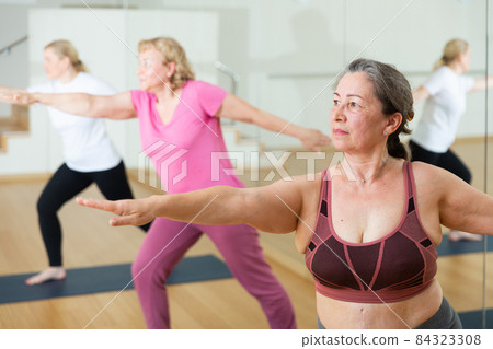 Mature women practicing yoga at group class 84323308