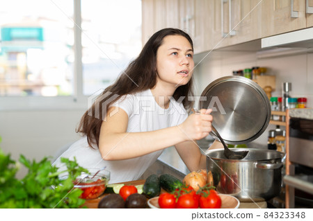 Portrait of young woman cooking at home Portrait of young woman cooking at home 84323348