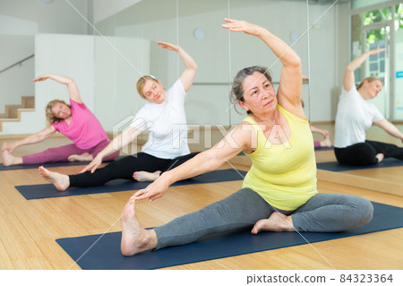 Three ladies are doing one-legged forward bend Three ladies are doing one-legged forward bend 84323364