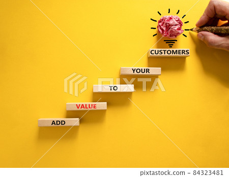 Add value to your customers symbol. Concept words 'Add value to your customers' on blocks on a yellow background, copy space. Businessman hand, light bulb icon. Business, customers value concept. Add value to your customers symbol. Concept words 'Add value to your customers' on blocks on a yellow background, copy space. Businessman hand, light bulb icon. Business, customers value concept. 84323481