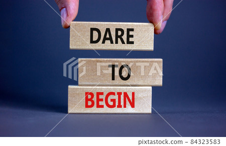 Dare to begin symbol. Wooden blocks with words 'Dare to begin'. Beautiful grey background, businessman hand. Business, dare to begin concept, copy space. Dare to begin symbol. Wooden blocks with words 'Dare to begin'. Beautiful grey background, businessman hand. Business, dare to begin concept, copy space. 84323583