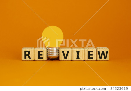 Review symbol. Wooden cubes with word 'review'. Yellow light bulb. Beautiful orange background. Business and review concept. Copy space. 84323619