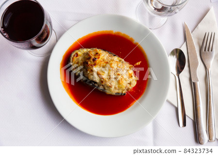 Baked stuffed eggplant served with spicy tomato sauce 84323734