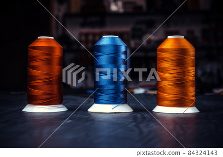 Three bright reel of silk thread on a black background in line Three bright reel of silk thread on a black background in line 84324143