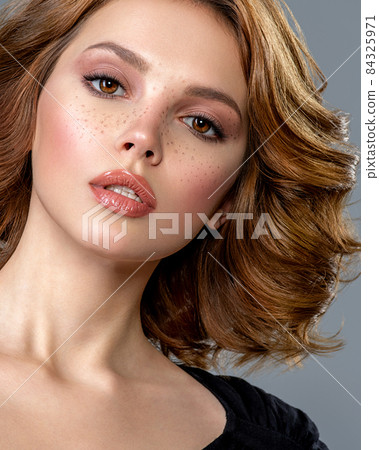 Beautiful brown haired with stylish short hairstyle. Woman with a curly hair. Beautiful young woman with freckles on face. Closeup portrait of an attractive girl with a brown makeup. Beautiful brown haired with stylish short hairstyle. Woman with a curly hair. Beautiful young woman with freckles on face. Closeup portrait of an attractive girl with a brown makeup. 84325971