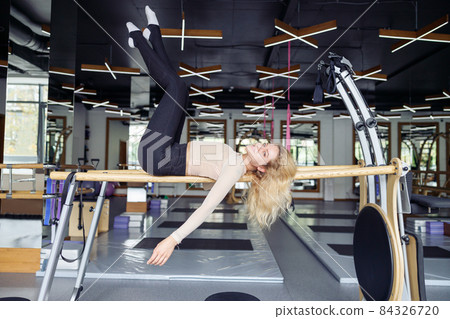 Side view of athletic woman having pilates workout in modern studio in the daytime 84326720