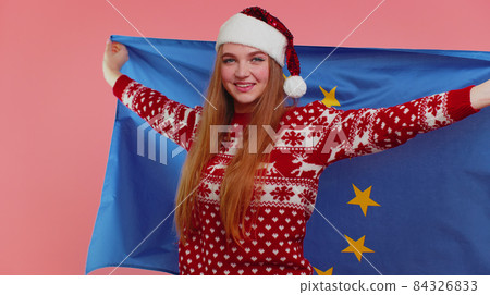 Girl in Christmas sweater waving European Union flag, smiling, cheering democratic laws human rights Girl in Christmas sweater waving European Union flag, smiling, cheering democratic laws human rights 84326833