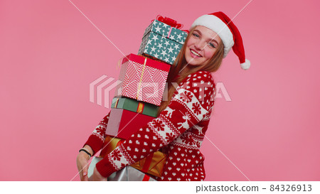 Woman in Christmas red sweater, Santa hat smiling holding many gift boxes New Year presents shopping Woman in Christmas red sweater, Santa hat smiling holding many gift boxes New Year presents shopping 84326913