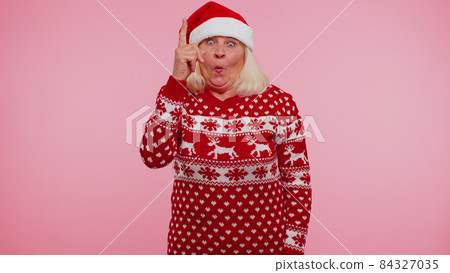 Grandmother in Christmas sweater make gesture raises finger came up with creative plan good idea 84327035
