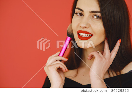 Woman in a black dress standing on a red background Woman in a black dress standing on a red background 84329233