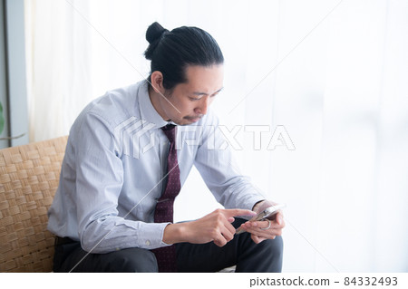 一位男性商人一邊看智能手機一邊思考,有一個複制空間 一位男性商人一邊看智能手機一邊思考,有一個複制空間 84332493