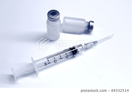 Vial of drugs or vaccine and 3 ml plastic syringe with needle isolated on the white background, blue tone color Vial of drugs or vaccine and 3 ml plastic syringe with needle isolated on the white background, blue tone color 84332514