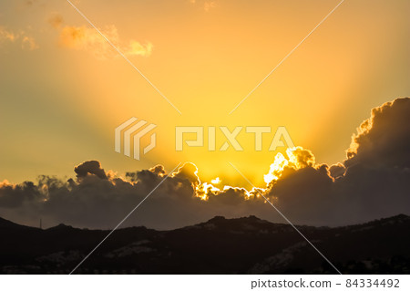 Background from a beautiful sunset with clouds and sunlights over mountanous coast. High quality photo 84334492