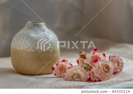 White and Yellow handmade ceramic vase with Bouquet of flower on Blush textured table cloth. White and Yellow handmade ceramic vase with Bouquet of flower on Blush textured table cloth. 84335214