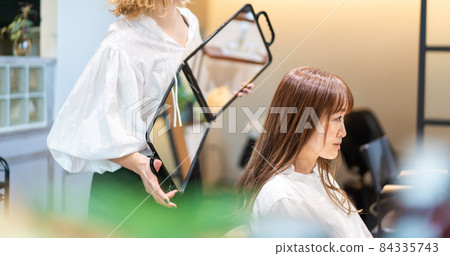 Hairdresser checking hairstyle with a mirror 84335743