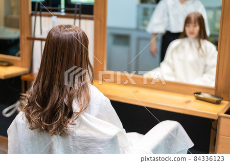 Hairdresser using a hair iron 84336123