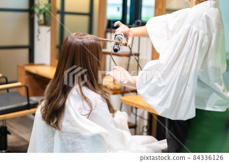 Hairdresser using a hair iron 84336126