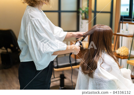 Hairdresser using a hair iron Hairdresser using a hair iron 84336132