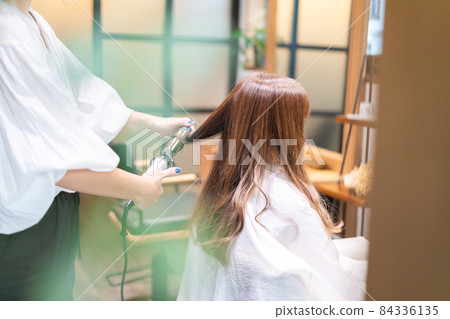 Hairdresser using a hair iron Hairdresser using a hair iron 84336135