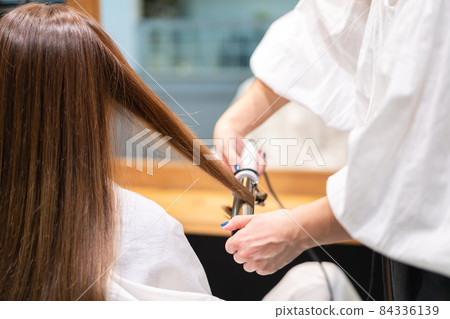 Hairdresser using a hair iron Hairdresser using a hair iron 84336139