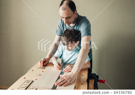 Cute little boy with pencil in hand making marks on wooden plank. Cute little boy with pencil in hand making marks on wooden plank. 84336780