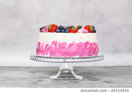 Delicate cake garnished with fresh strawberries blueberries on a gray plain background. Festive dessert Delicate cake garnished with fresh strawberries blueberries on a gray plain background. Festive dessert 84338830