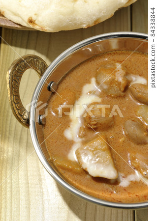 A bird's-eye view of Massaman curry and naan, which contains a lot of ingredients such as chicken and peanuts. 84338844