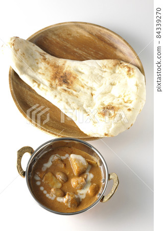 A bird's-eye view of Massaman curry and naan containing many ingredients such as chicken and peanuts on a white background 84339270