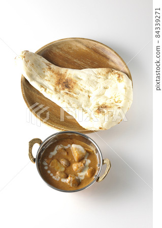 A bird's-eye view of Massaman curry and naan containing many ingredients such as chicken and peanuts on a white background 84339271