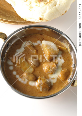 A bird's-eye view of Massaman curry and naan containing many ingredients such as chicken and peanuts on a white background 84339274