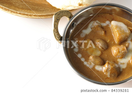 A bird's-eye view of Massaman curry and naan containing many ingredients such as chicken and peanuts on a white background 84339281
