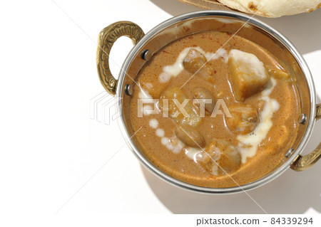 A bird's-eye view of Massaman curry and naan containing many ingredients such as chicken and peanuts on a white background 84339294