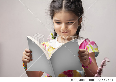 Little girl reading a story book with blank cover covers mock-up series Little girl reading a story book with blank cover covers mock-up series 84339584