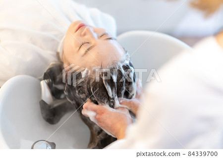 Female receiving steam treatment at a hair dressing Female receiving steam treatment at a hair dressing 84339700