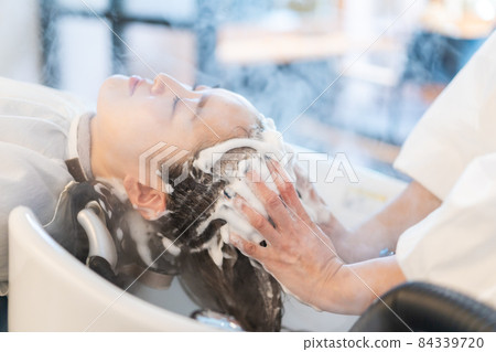 Female receiving steam treatment at a hair dressing Female receiving steam treatment at a hair dressing 84339720