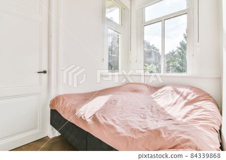 Miniature bedroom with a large bed by the window covered with a pink soft blanket 84339868