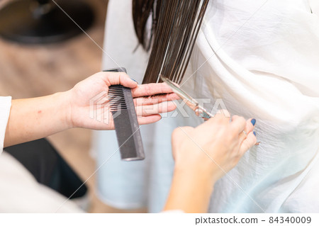 Hairdresser doing female haircut 84340009