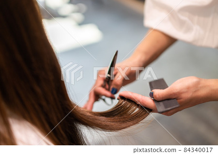 Hairdresser doing female haircut Hairdresser doing female haircut 84340017