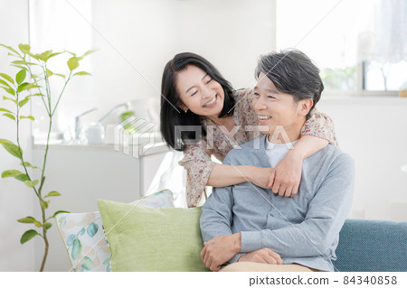 中年男人坐在客廳的沙發上，中年女人抱回中年情愛 84340858