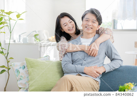 Middle-aged man sitting on the sofa in the living room and middle-aged woman hugging back Middle-aged love love 84340862