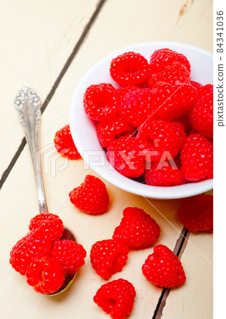 bunch of fresh raspberry on a bowl and white table 84341036